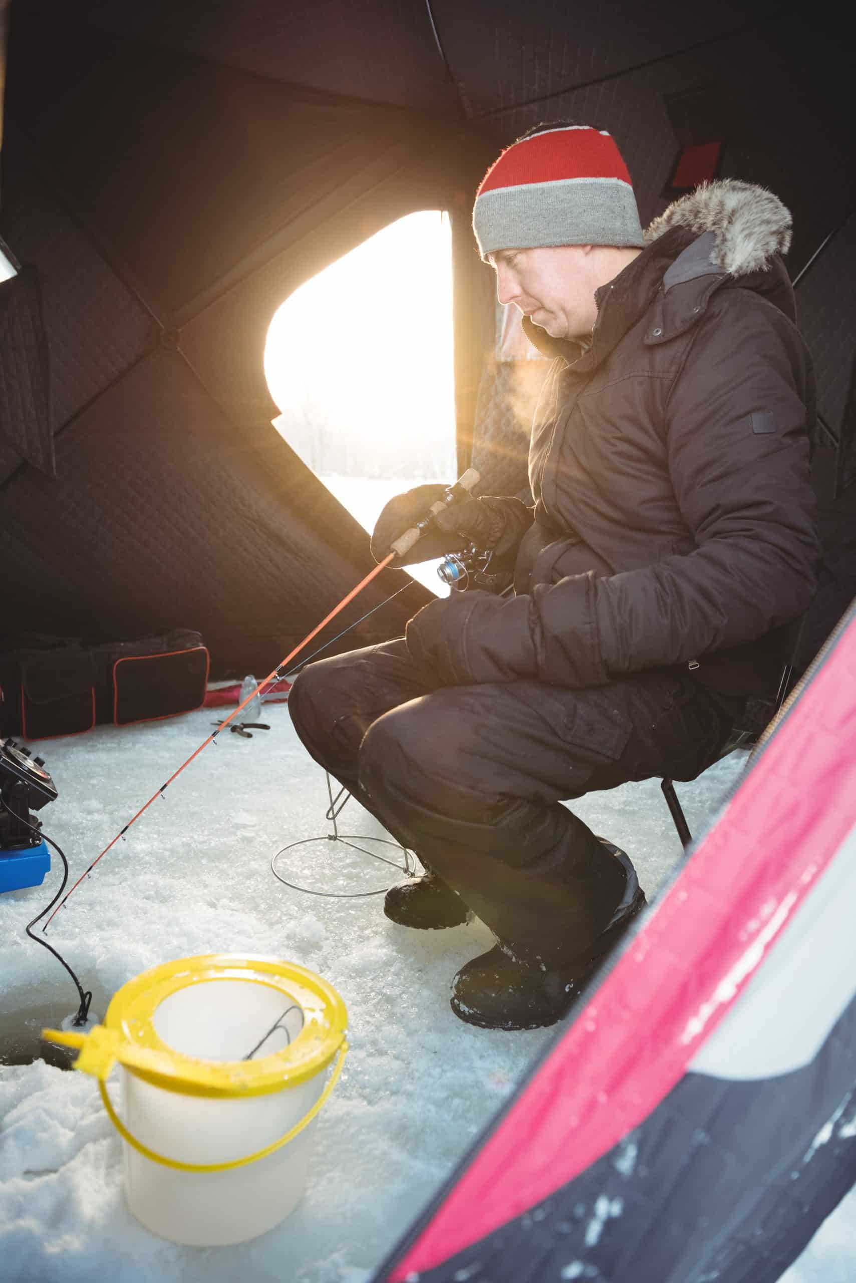 Angler jigging a small ice fishing lure through a hole in the ice
